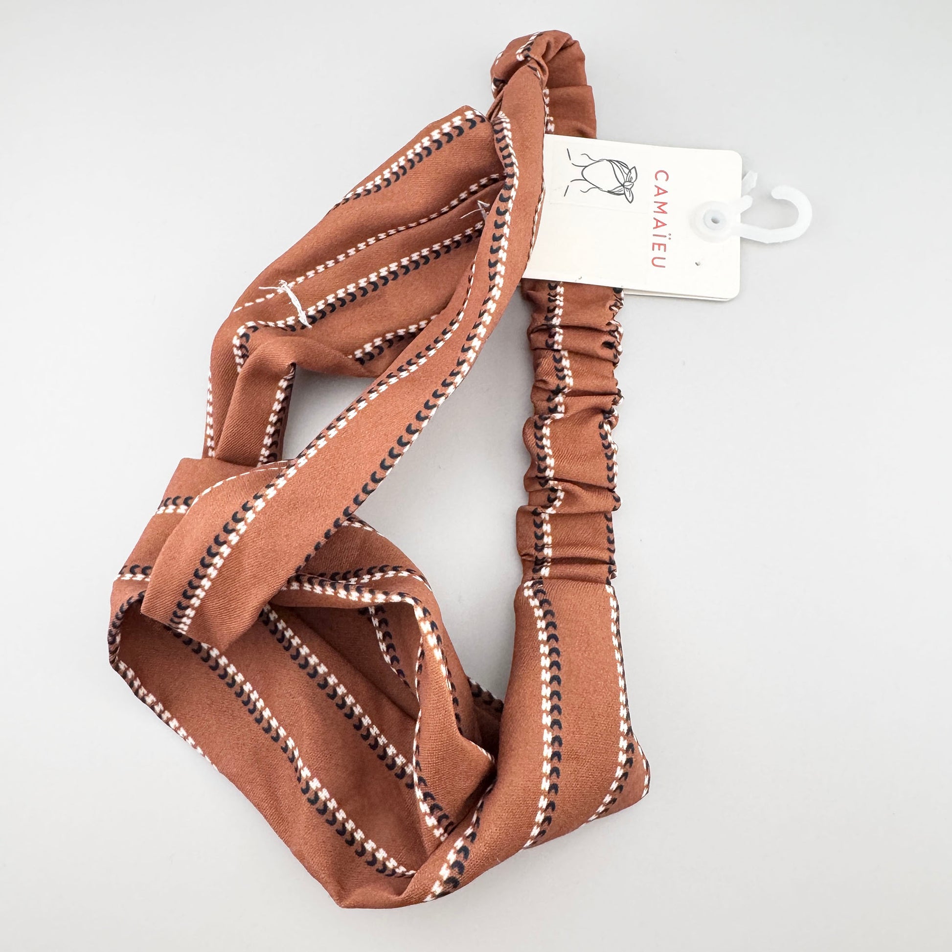 Brown striped Camaïeu headband folded to show its soft fabric and gathered elastic back
