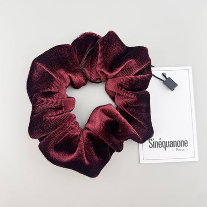 Burgundy velvet scrunchie by Sinequanone displayed open beside its branded tag