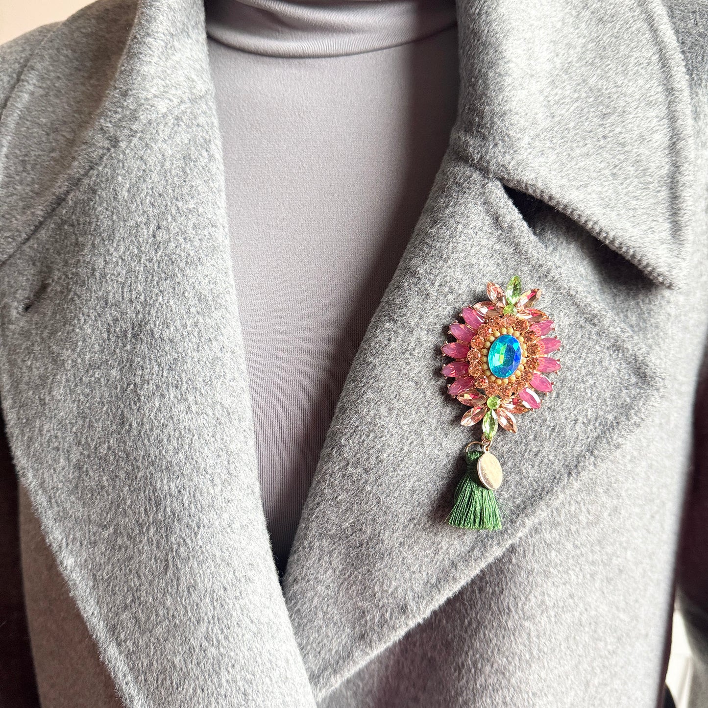 Colorful crystal brooch Sonata worn on a coat with a vivid tassel detail