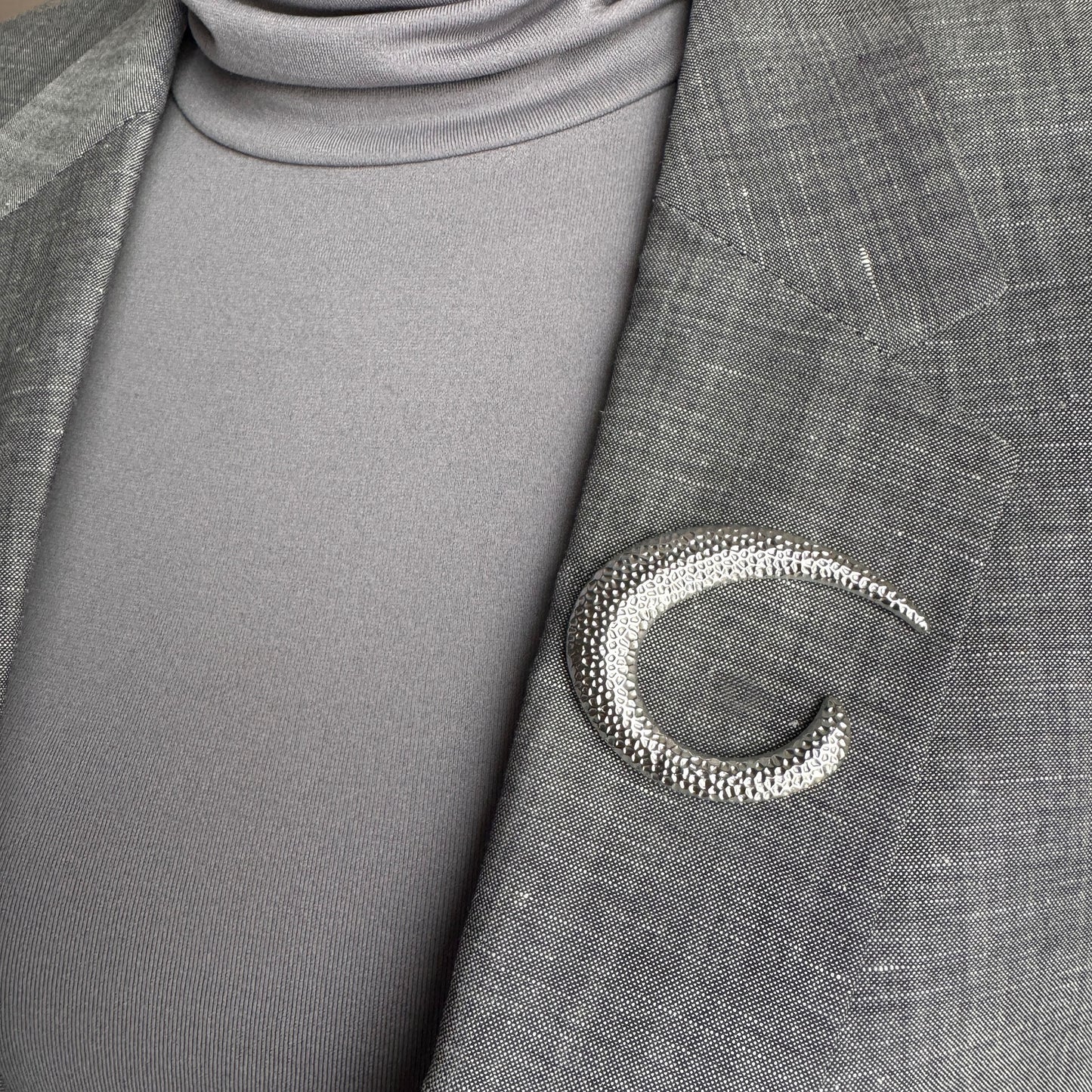 Silver crescent brooch Sonata worn on a blazer with a sculptural hammered finish