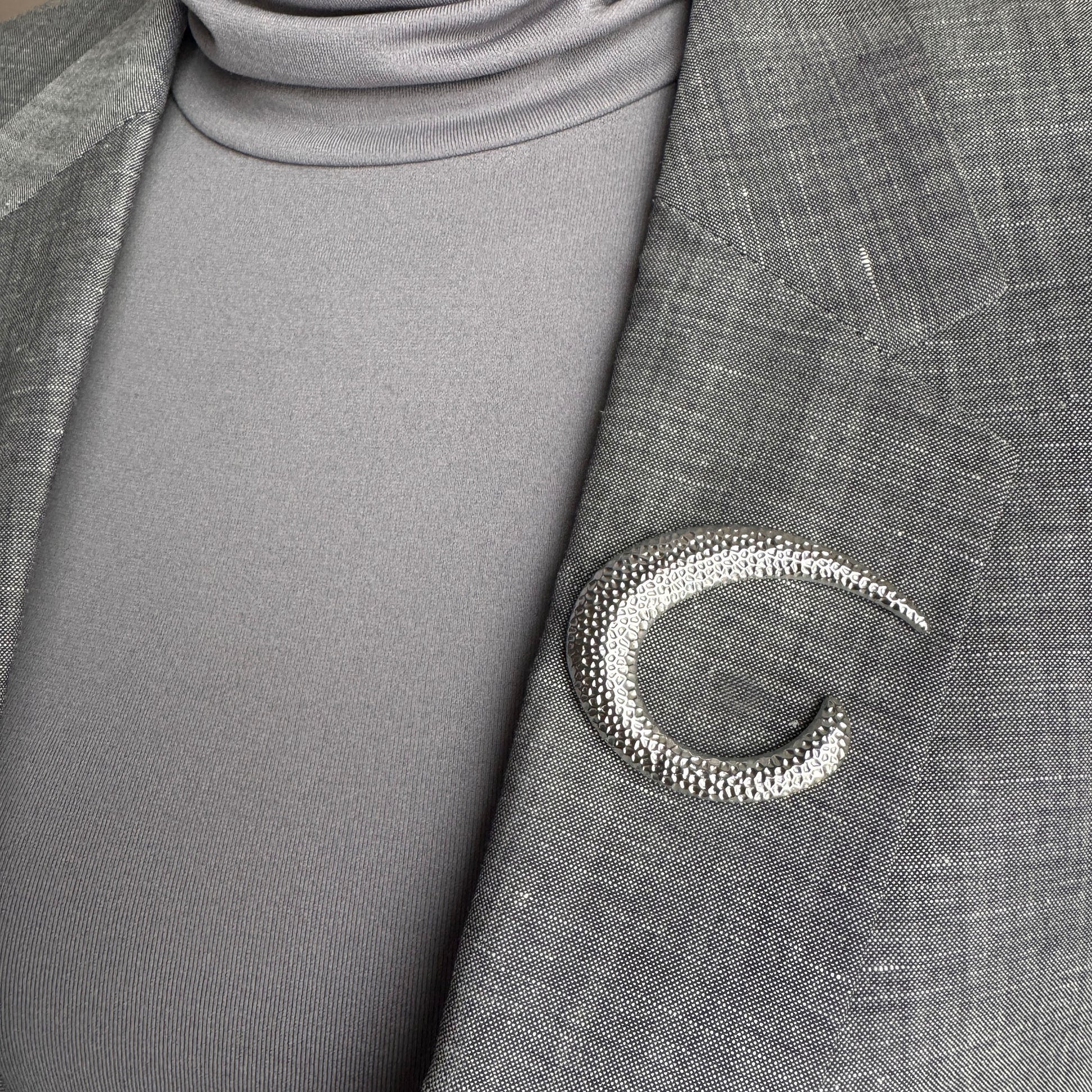 Silver crescent brooch Sonata worn on a blazer with a sculptural hammered finish