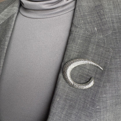 Silver crescent brooch Sonata worn on a blazer with a sculptural hammered finish