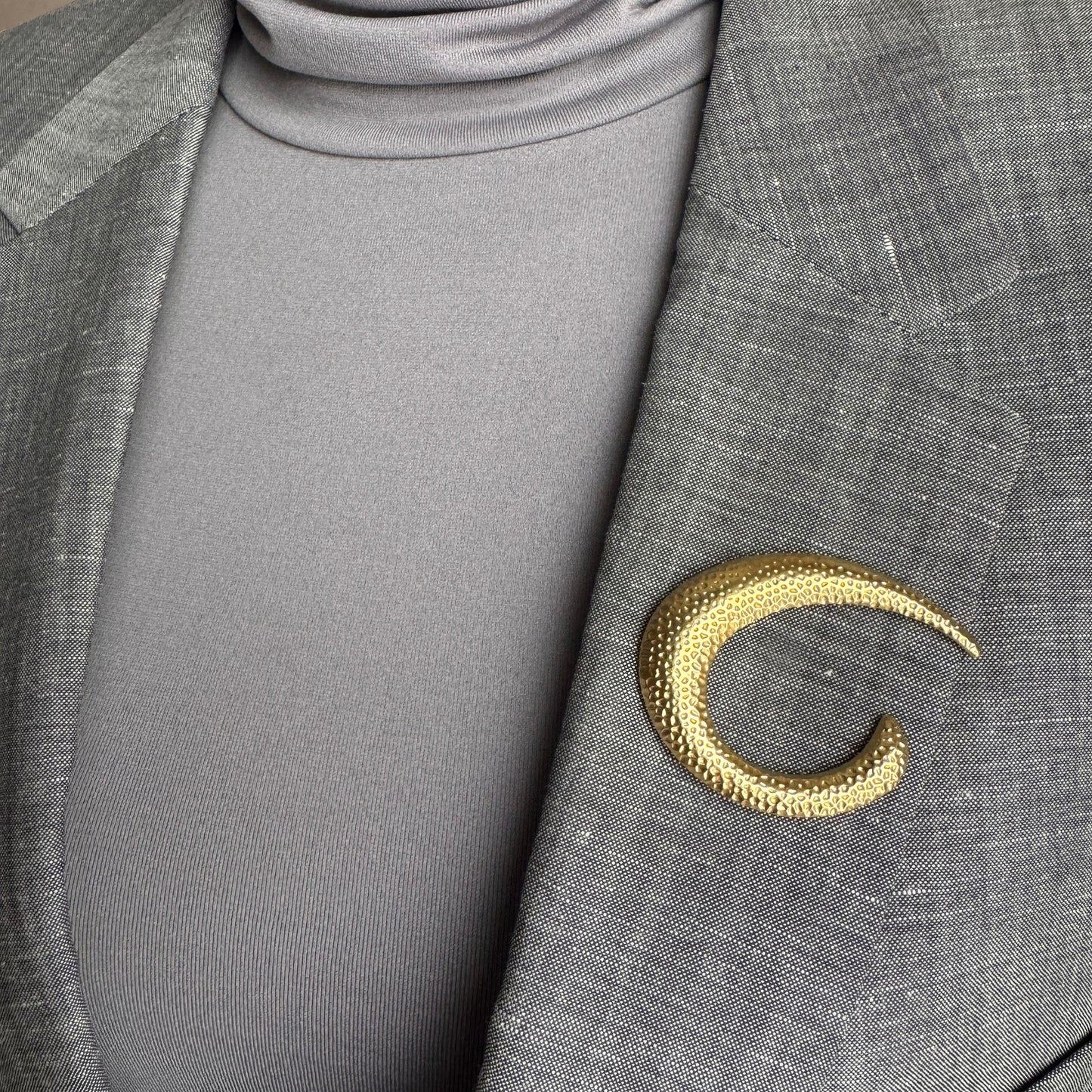 Gold crescent brooch Sonata worn on a blazer with a textured hammered finish
