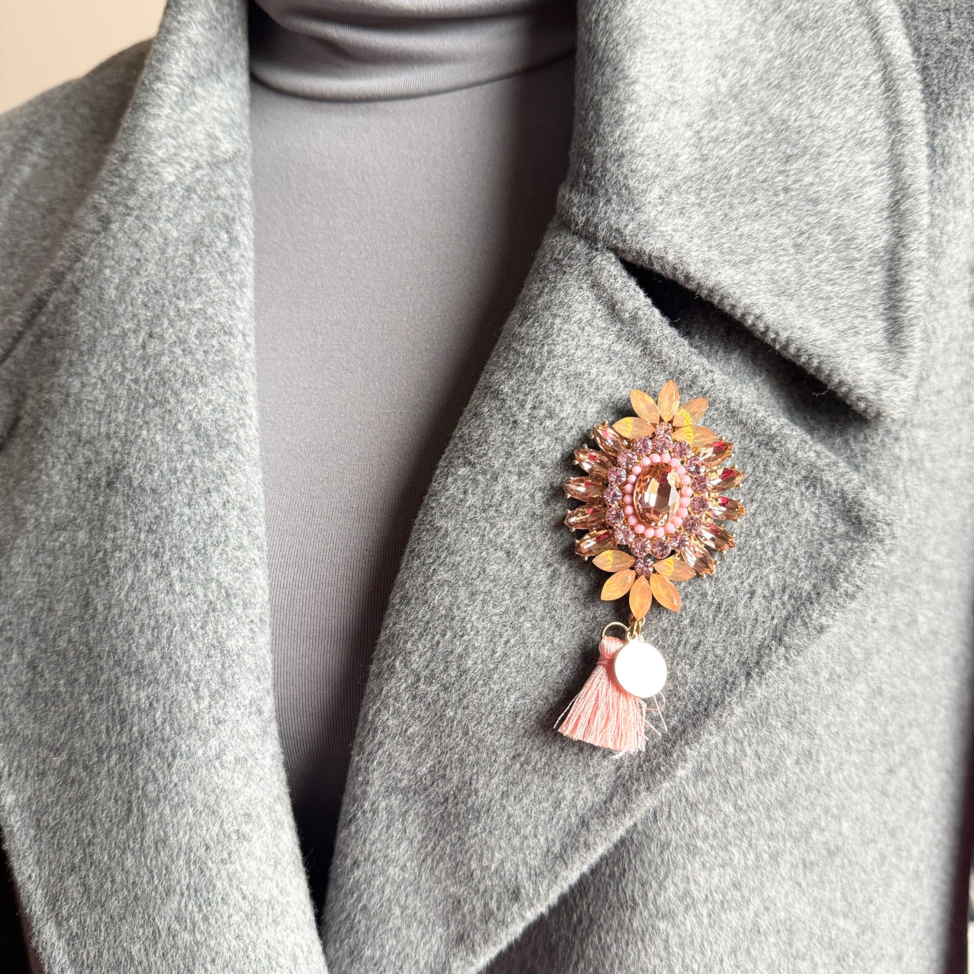 Crystal flower brooch Sonata worn on a coat with a soft tassel detail
