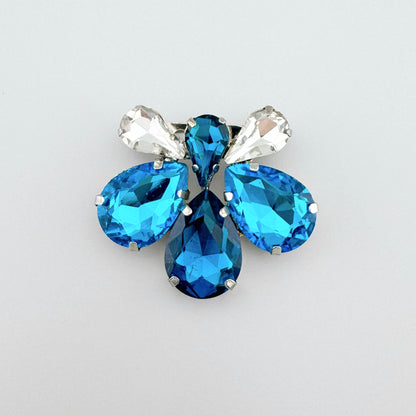 Brosche Sonata mit blauen Kristallen in Blumenform und facettiertem Glanz