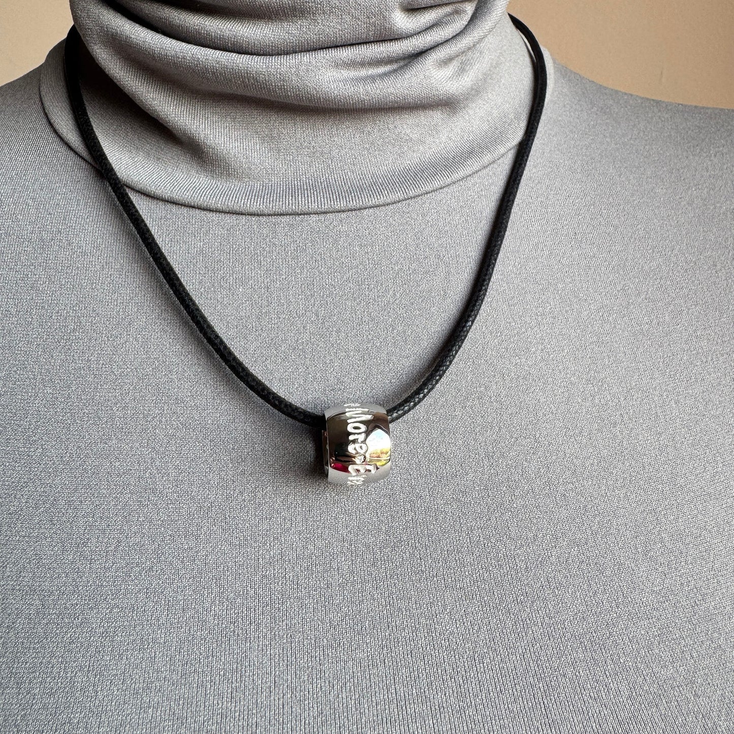 Cylindrical pendant necklace worn on the neck with a subtle engraved detail