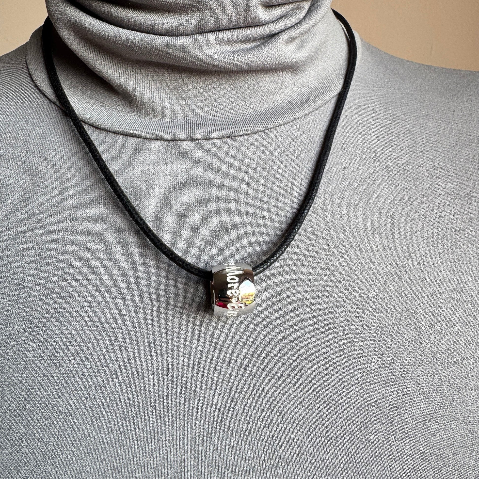 Cylindrical pendant necklace worn on the neck with a subtle engraved detail