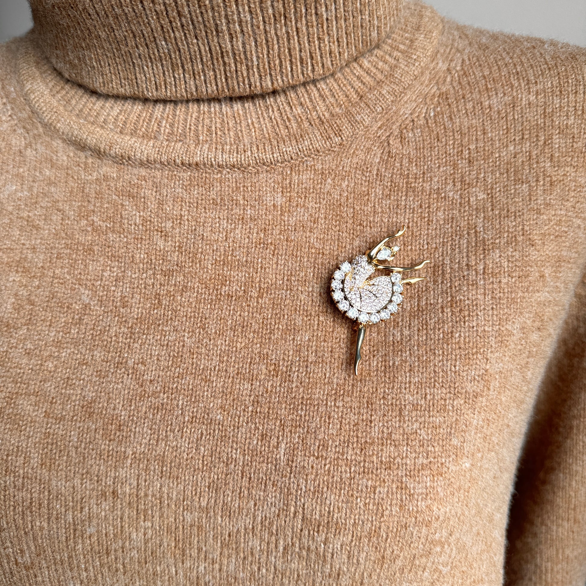 Golden ballerina brooch on neutral fabric styled for evening elegance