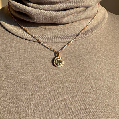 Elegant gold-plated necklace with round zirconia pendant styled on a beige top