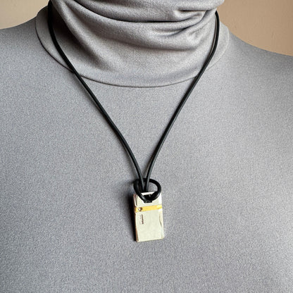 Silver pendant on red and black cord, calm geometric accent near the collarbone