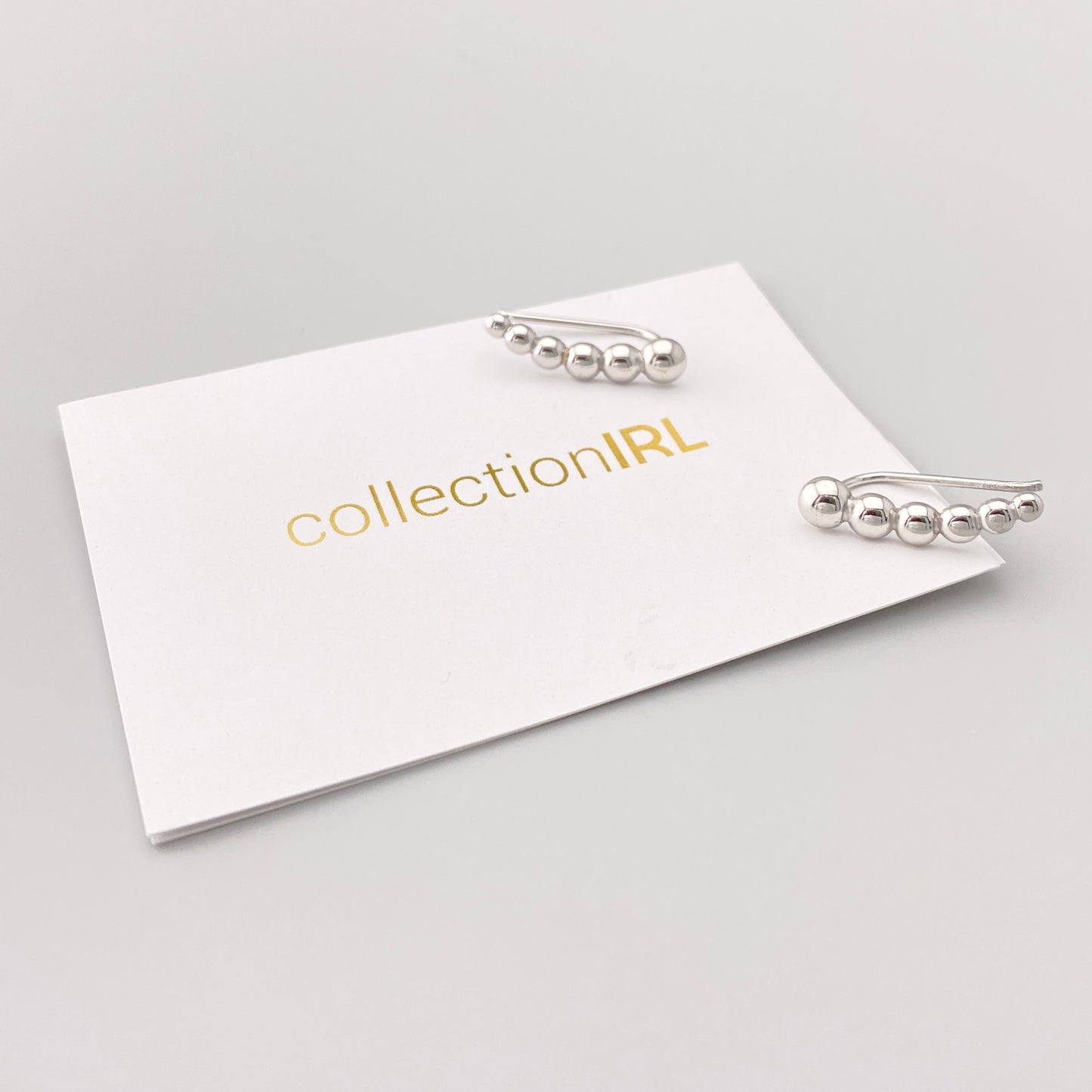 Minimal silver ball ear cuffs with smooth polished finish on display card