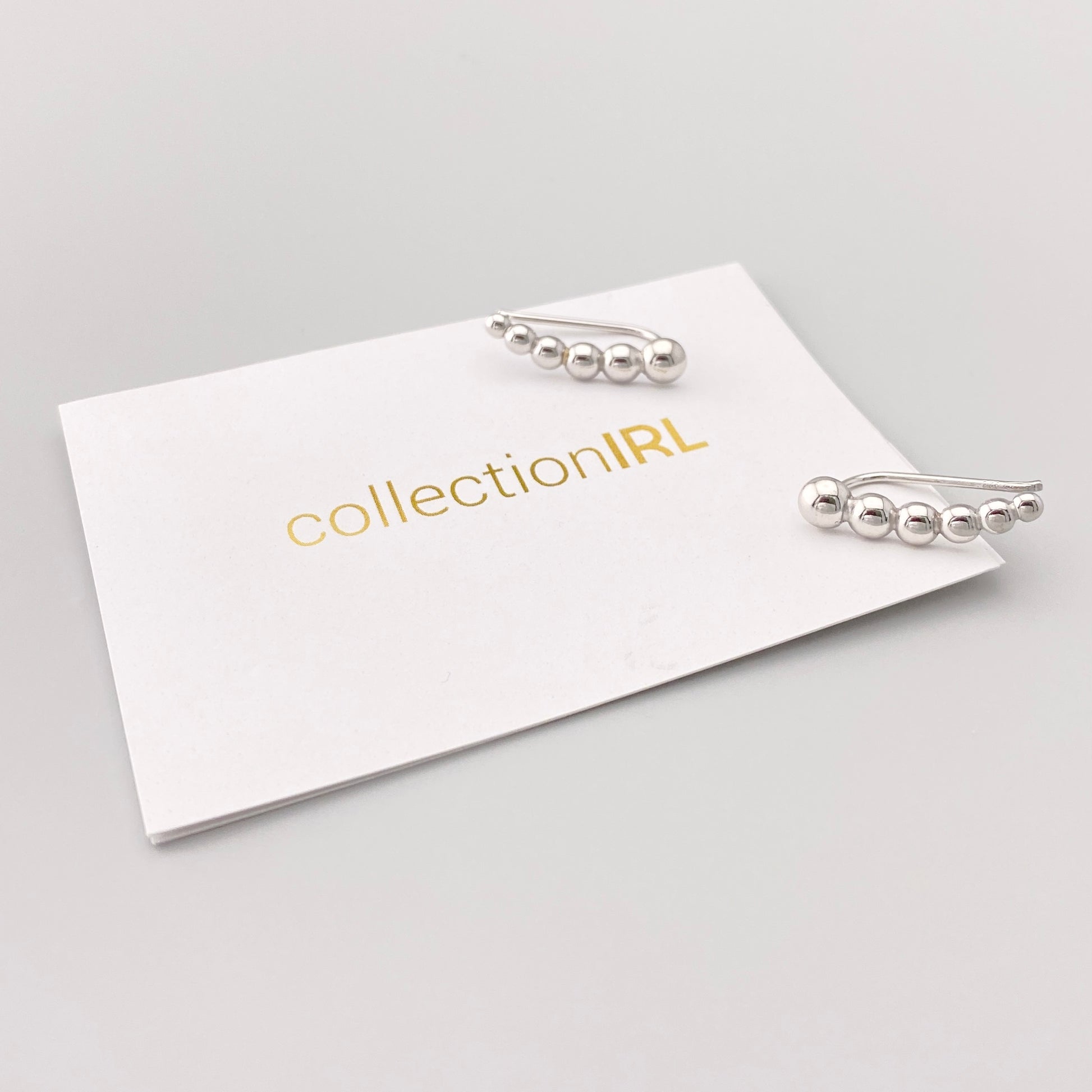 Minimal silver ball ear cuffs with smooth polished finish on display card