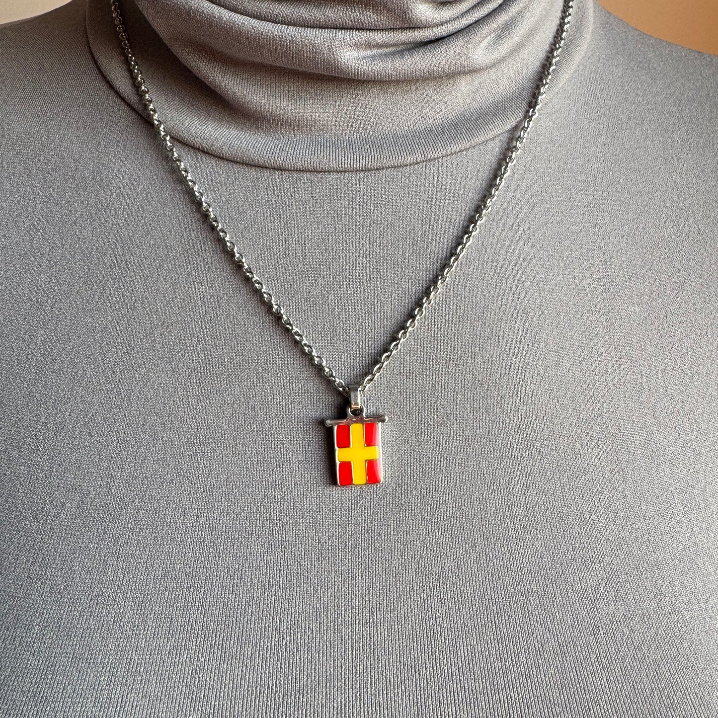 Enamel pendant necklace worn close to collarbone, quiet modern accent