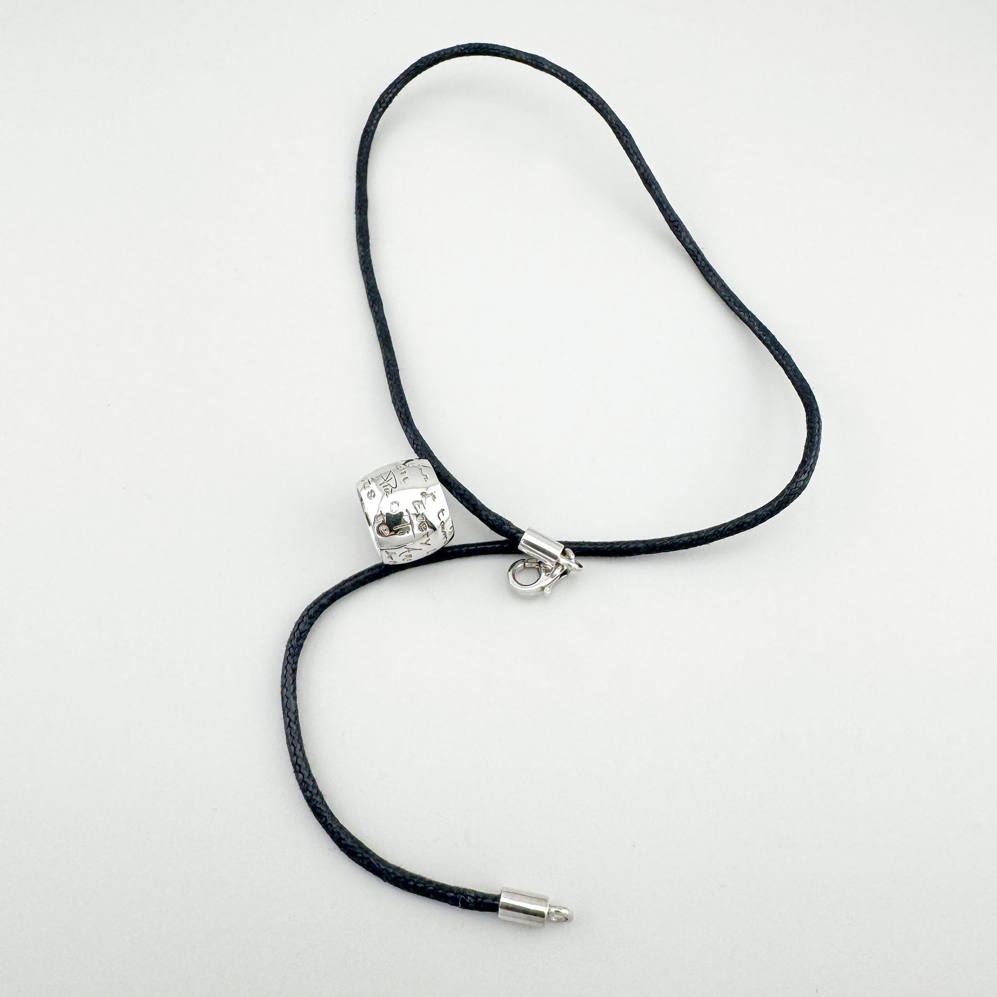 Деталь підвіски з гравіруванням і діамантом на чорному шнурку, стриманий блиск