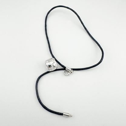 Деталь підвіски з гравіруванням і діамантом на чорному шнурку, стриманий блиск