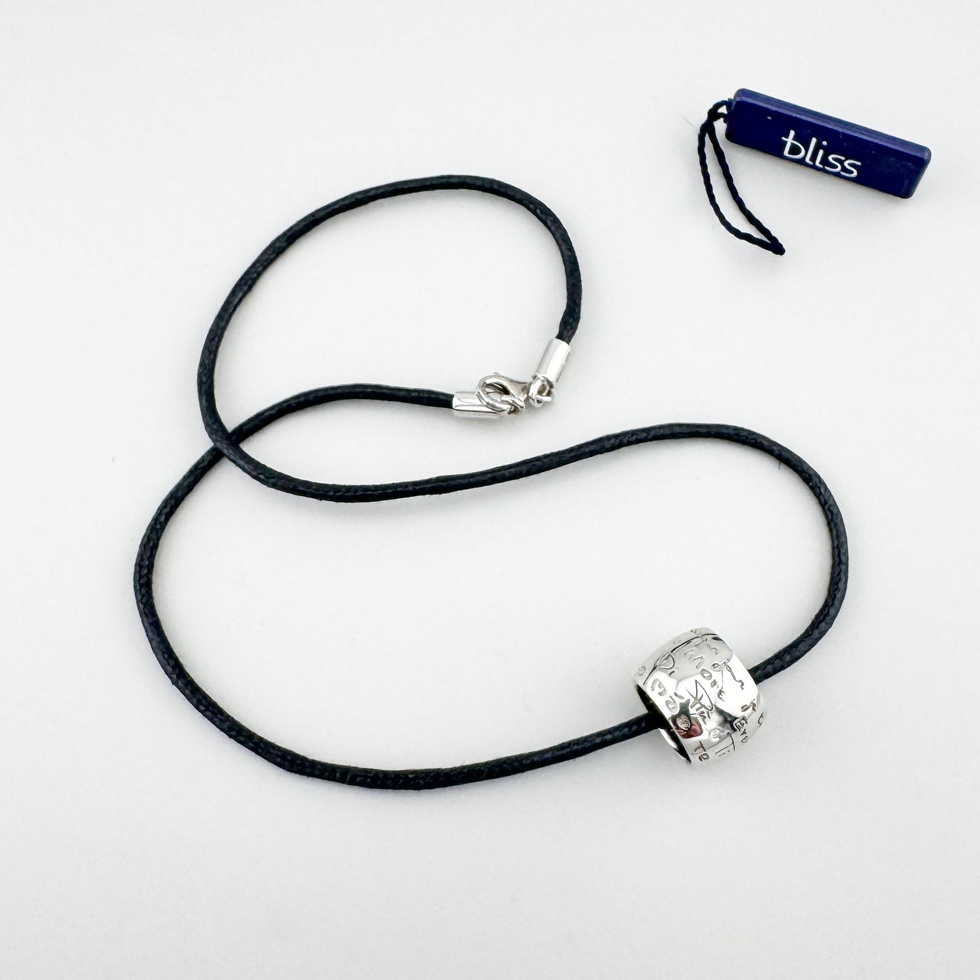 Srebrny naszyjnik z grawerem i diamentem na czarnym sznurku, spokojny akcent