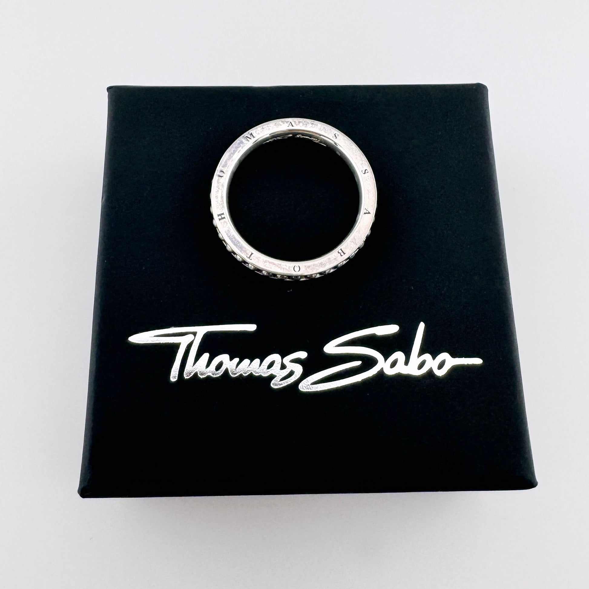 Bague en argent Thomas Sabo avec gravure de la marque et bordure finement perlée sur son écrin noir