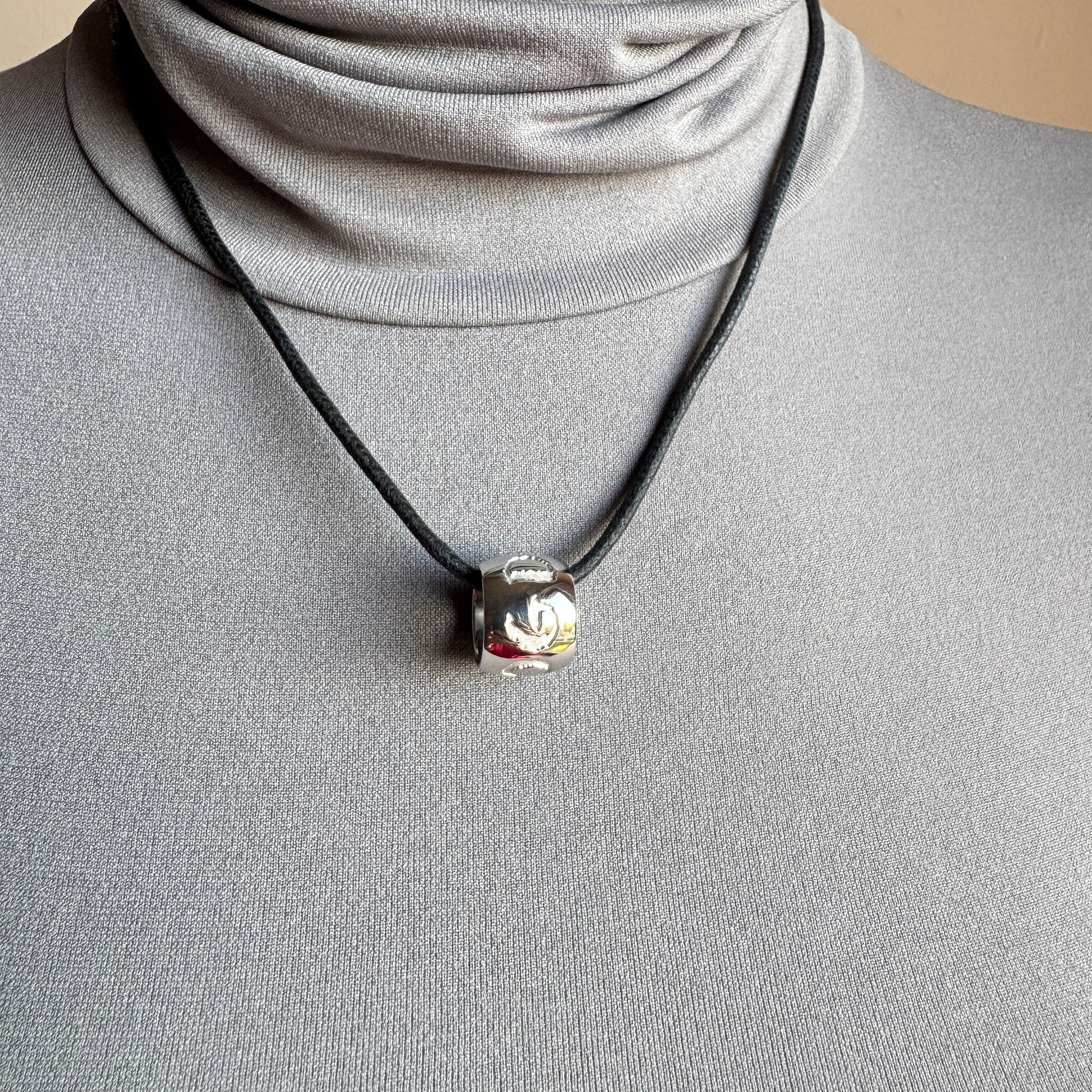 Engraved symbols necklace worn close to the neck with subtle shine and calm presence