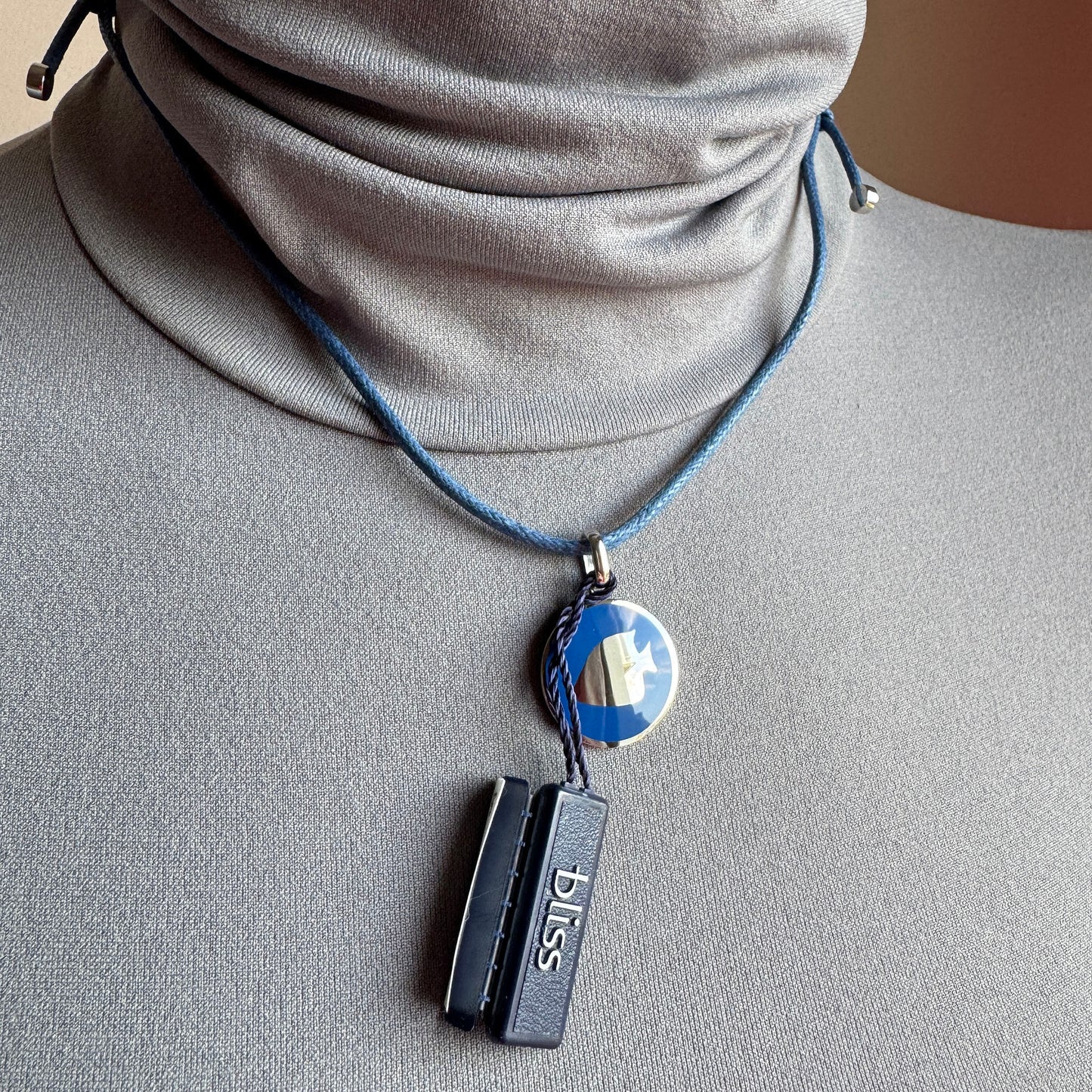 Rectangular pendant necklace with subtle gold accent worn on a black cord