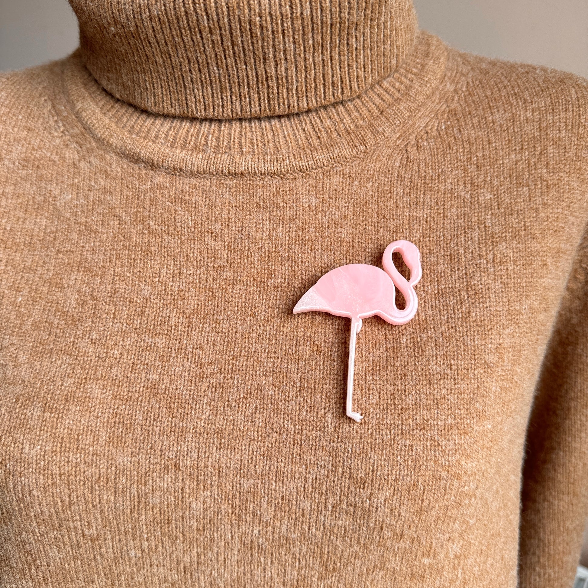 Light pink flamingo brooch worn on beige knitwear