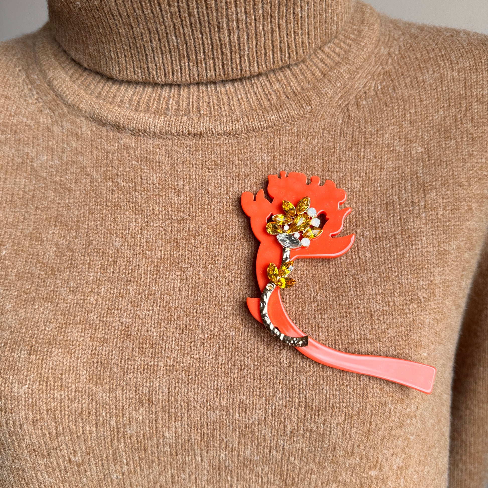 Bold orange acrylic flower brooch with yellow crystals on sweater