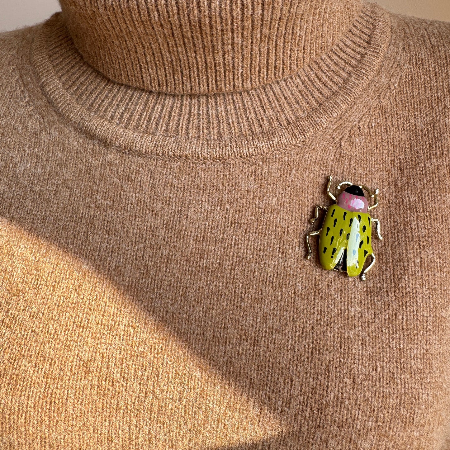 Bright green beetle brooch with golden legs worn on sweater in vintage style