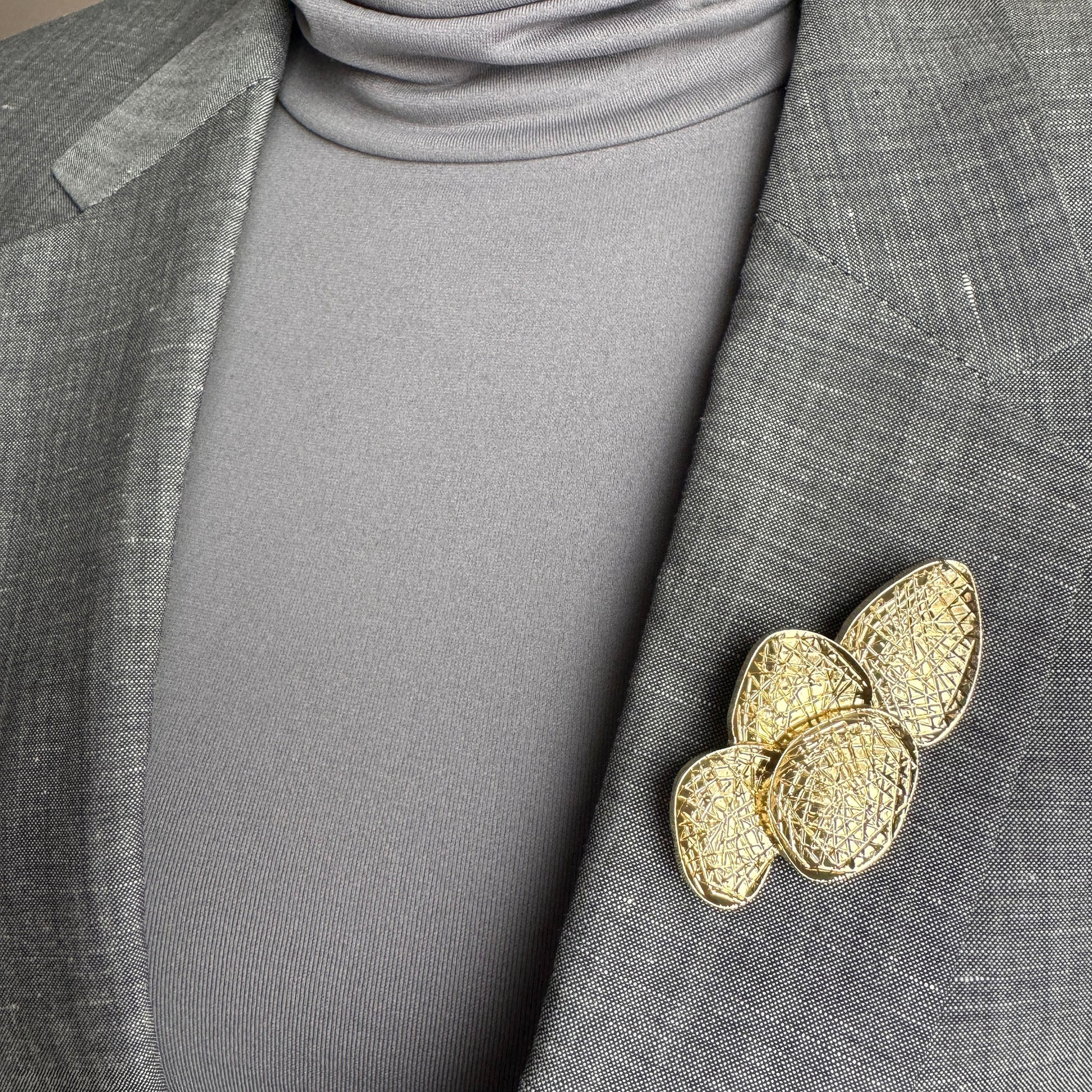 Gold geometric brooch Sonata worn on a blazer with a textured layered design