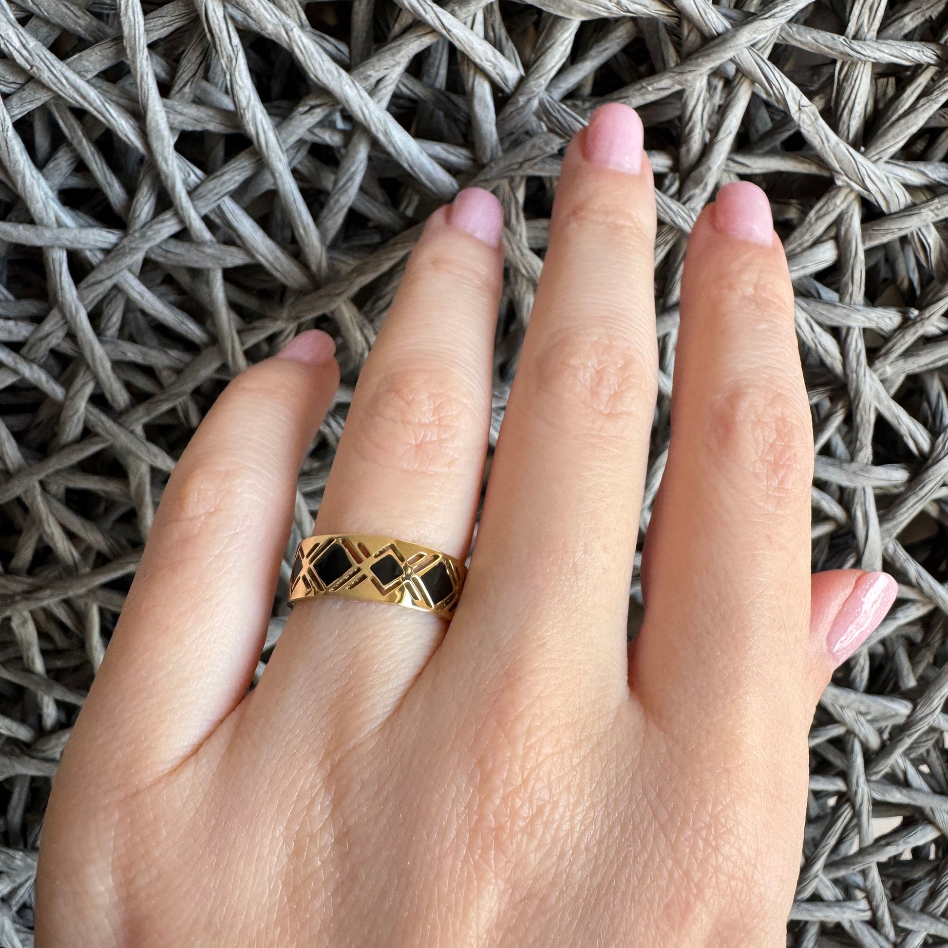 Gold-plated IRL ring with black enamel geometric design on a woman's hand