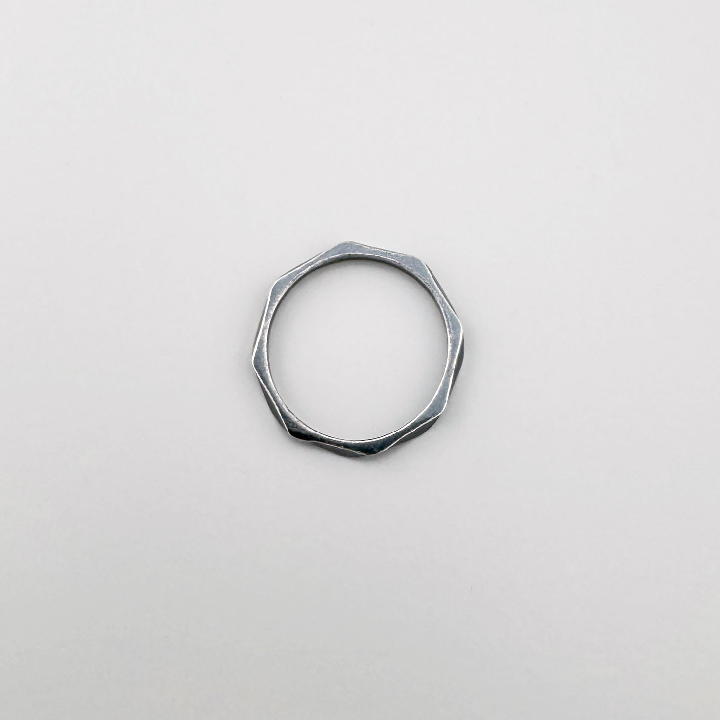 Srebrny pierścionek geometryczny 925 z delikatnymi załamaniami, spokojny minimalizm na jasnym tle