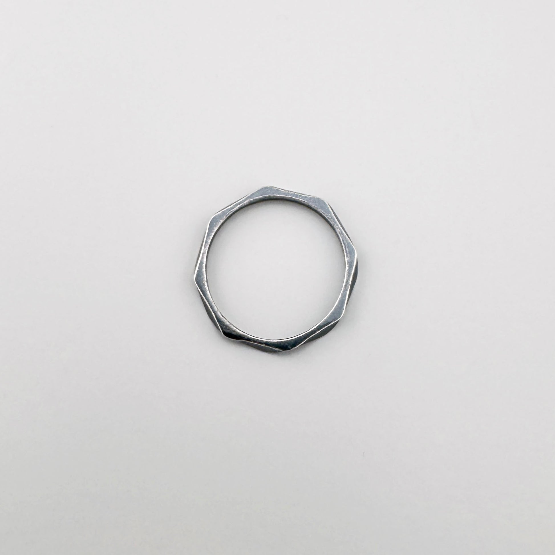 Srebrny pierścionek geometryczny 925 z delikatnymi załamaniami, spokojny minimalizm na jasnym tle