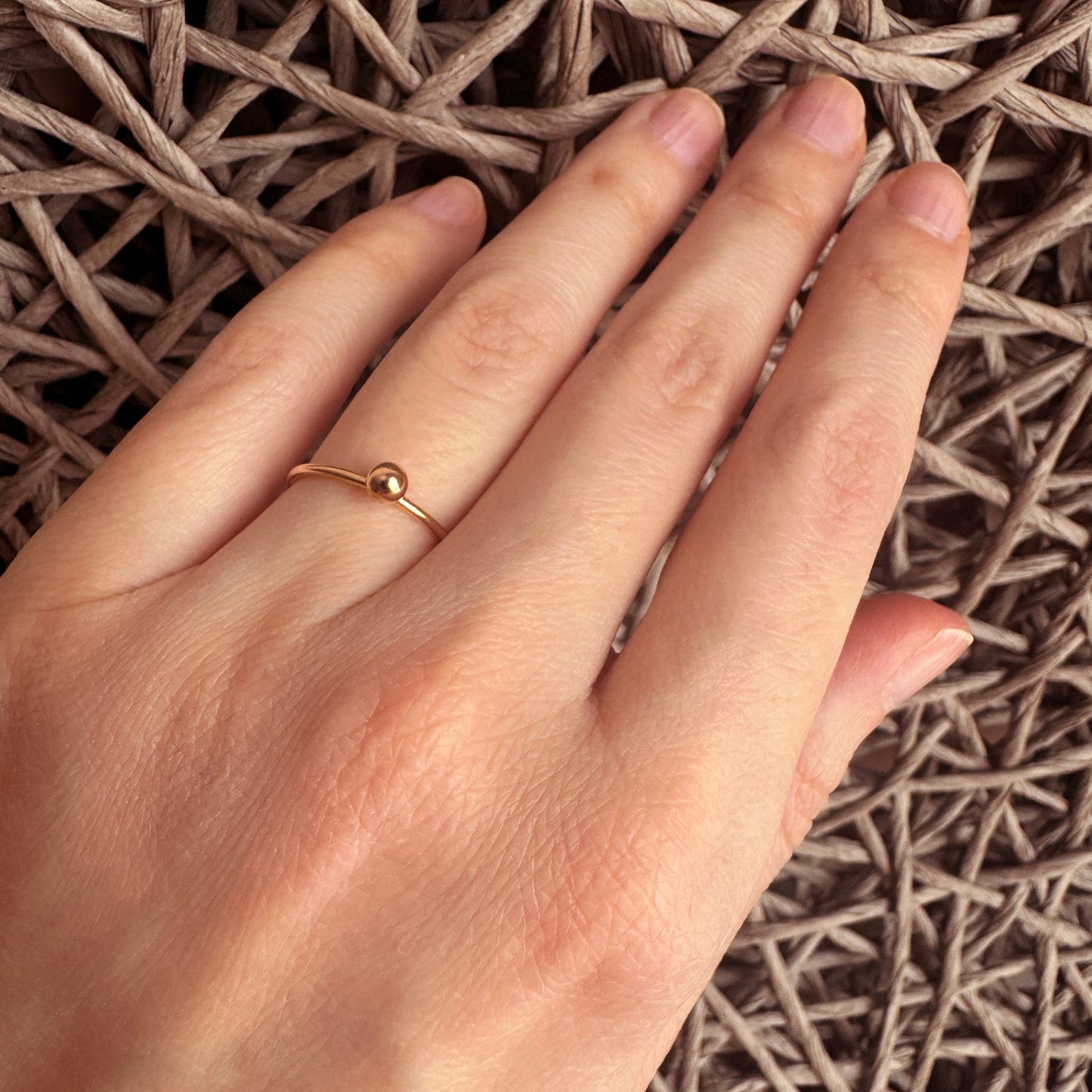 Gold ball ring LULU Copenhagen worn on the hand with a slim minimalist band