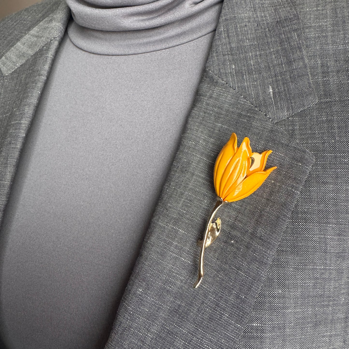 Gold flower brooch Sonata worn on a blazer with a slender curved stem