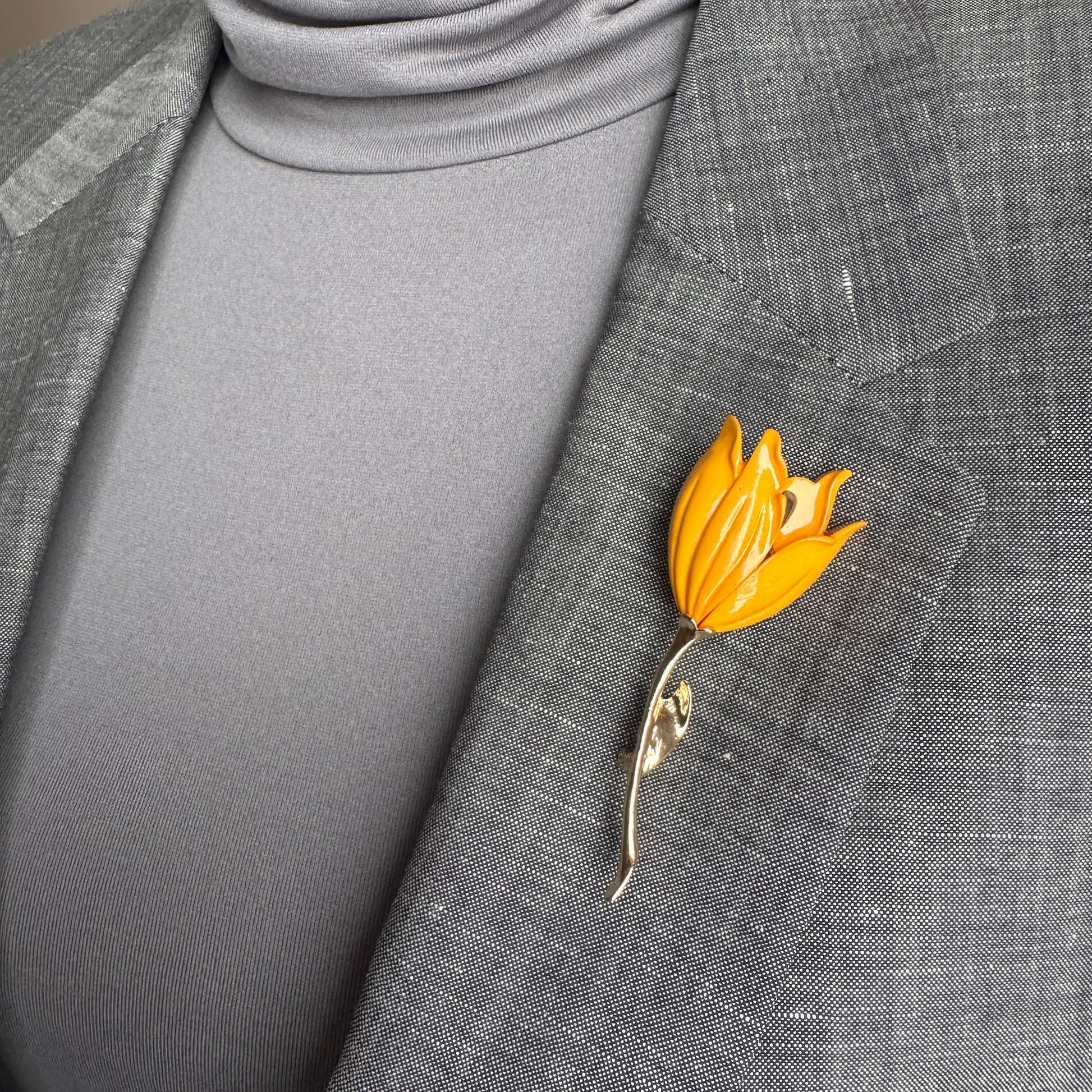 Gold flower brooch Sonata worn on a blazer with a slender curved stem