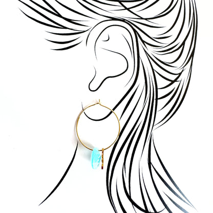 Gold IRL hoop earrings with light blue stone and star charm worn on ear illustration