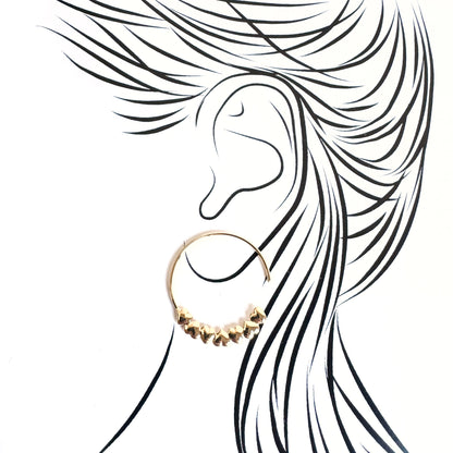 Delicate gold hoop earrings with heart details illustrated on an ear silhouette