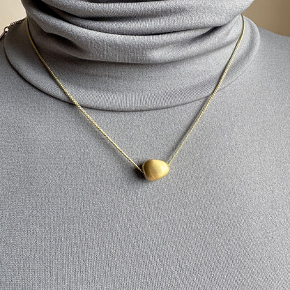 Gold Pilgrim necklace with soft matte pendant worn elegantly on neck