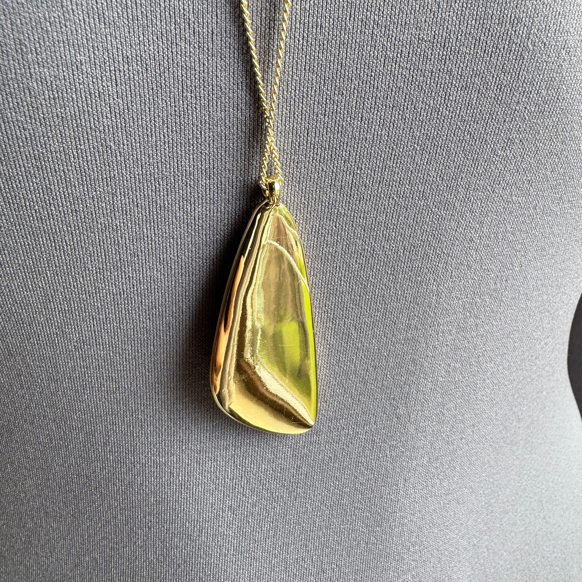 Collier Pilgrim doré avec pendentif large disposé sur fond clair