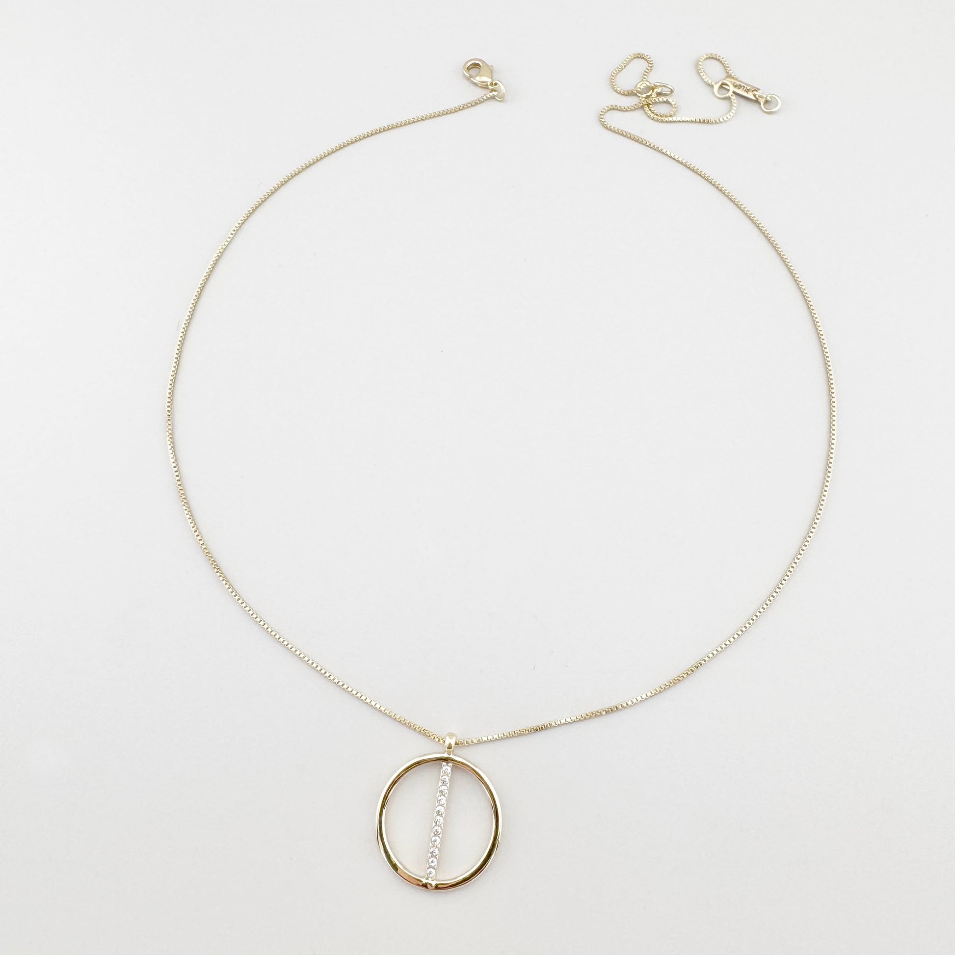 Collier Pilgrim doré avec pendentif rond et zirconias disposé sur fond clair
