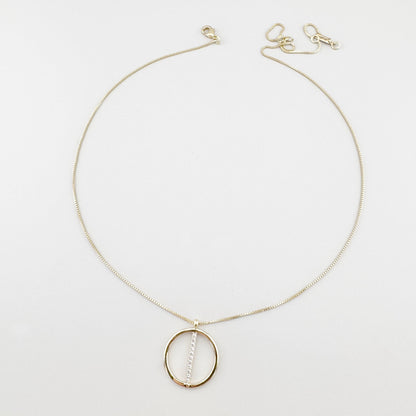 Collier Pilgrim doré avec pendentif rond et zirconias disposé sur fond clair