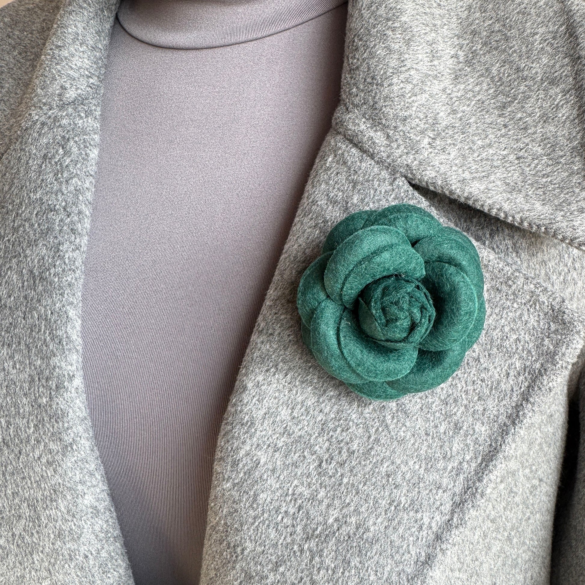 Green wool felt brooch styled on coat as modern floral detail