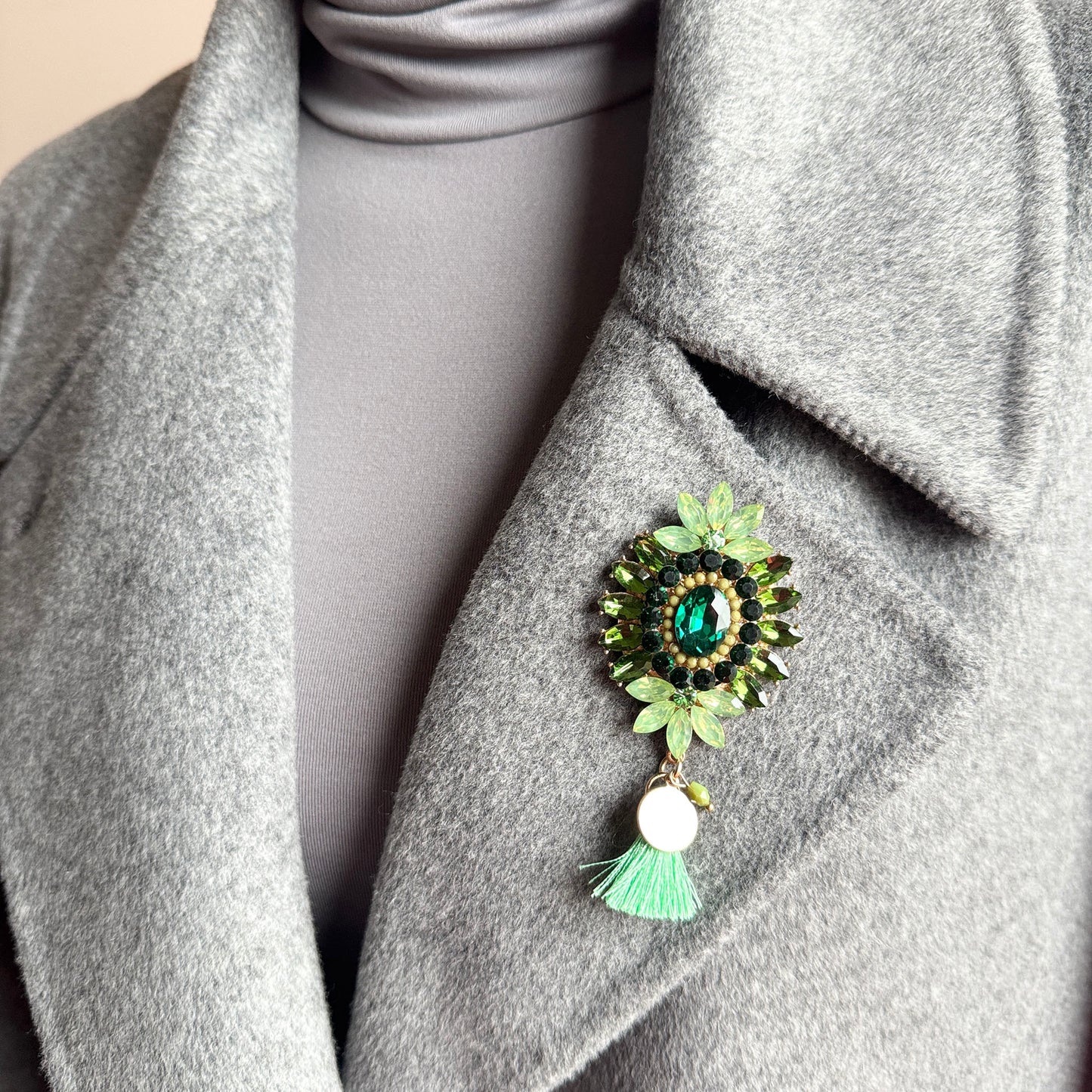 Green crystal flower brooch Sonata worn on a blazer with a soft tassel