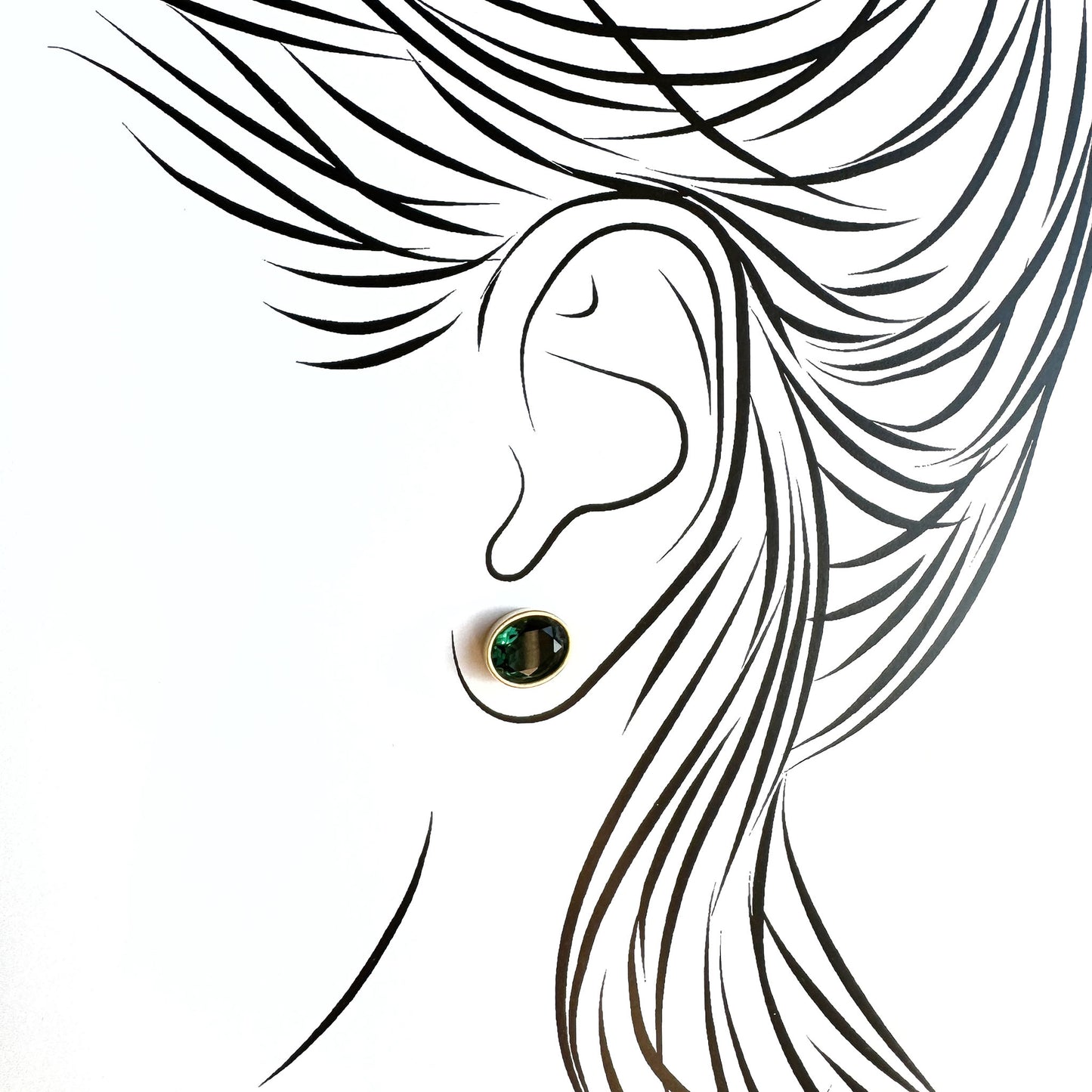 Gold plated green quartz stud earrings worn on ear with subtle glow