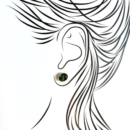 Gold plated green quartz stud earrings worn on ear with subtle glow