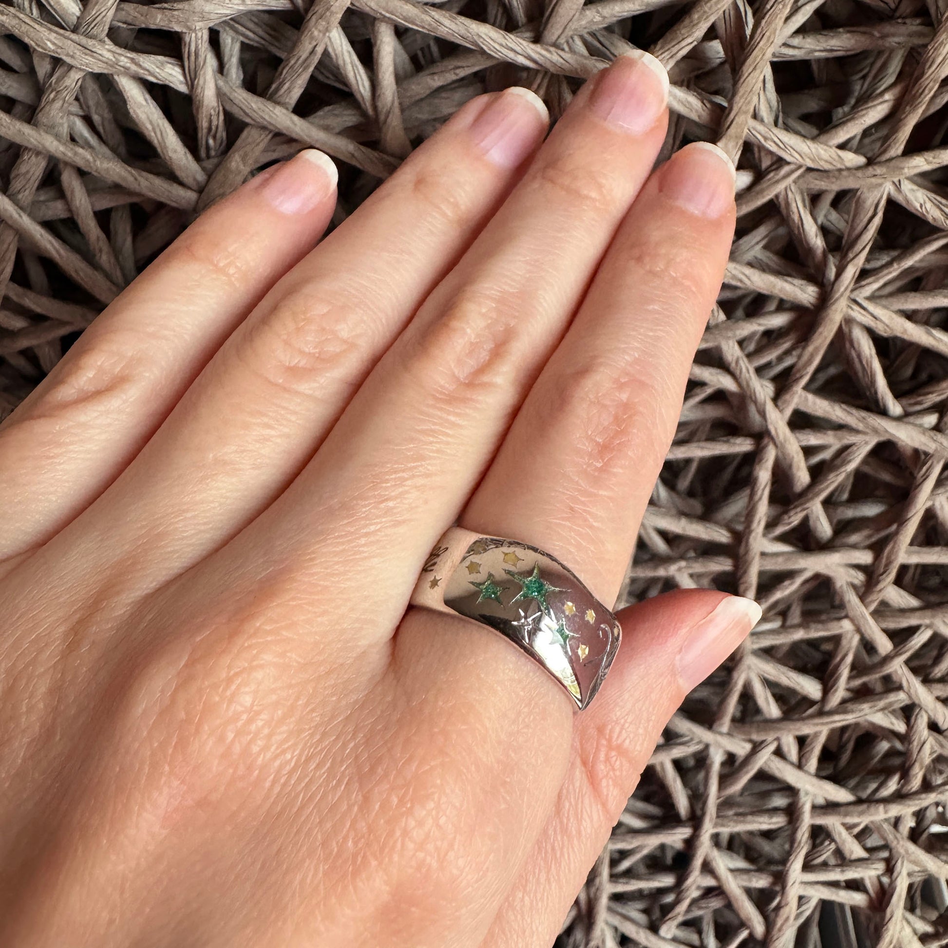 Green star ring worn on the hand with a polished silver-toned surface