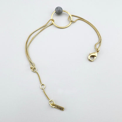 Pulsera con piedra gris y brillo dorado, detalle minimalista de estilo sereno