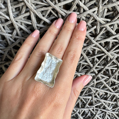 Rectangular silver ring with patina worn on finger with textured edges