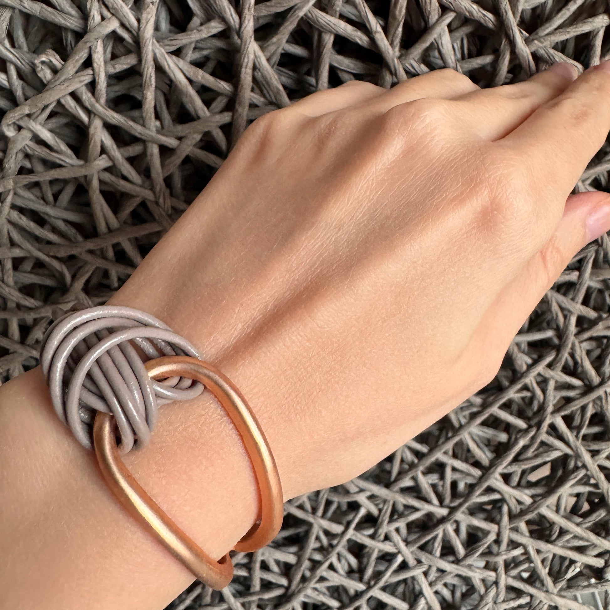 Knot bracelet Sonata worn on the wrist with gray cords and a gold element