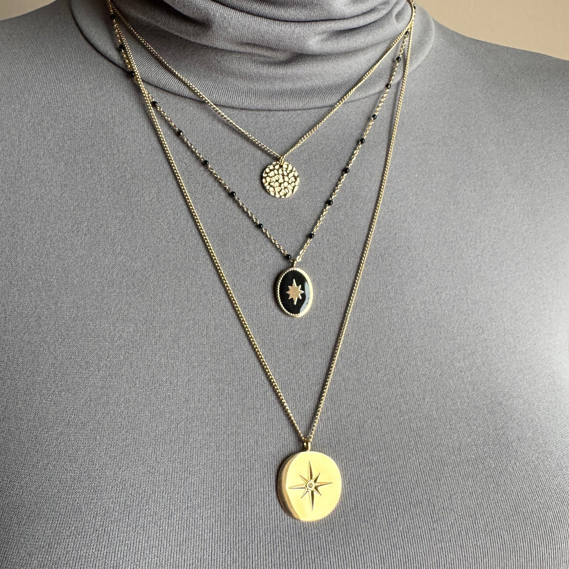 Layered medallion necklace IRL worn on the neck with black beads and gold-tone pendants