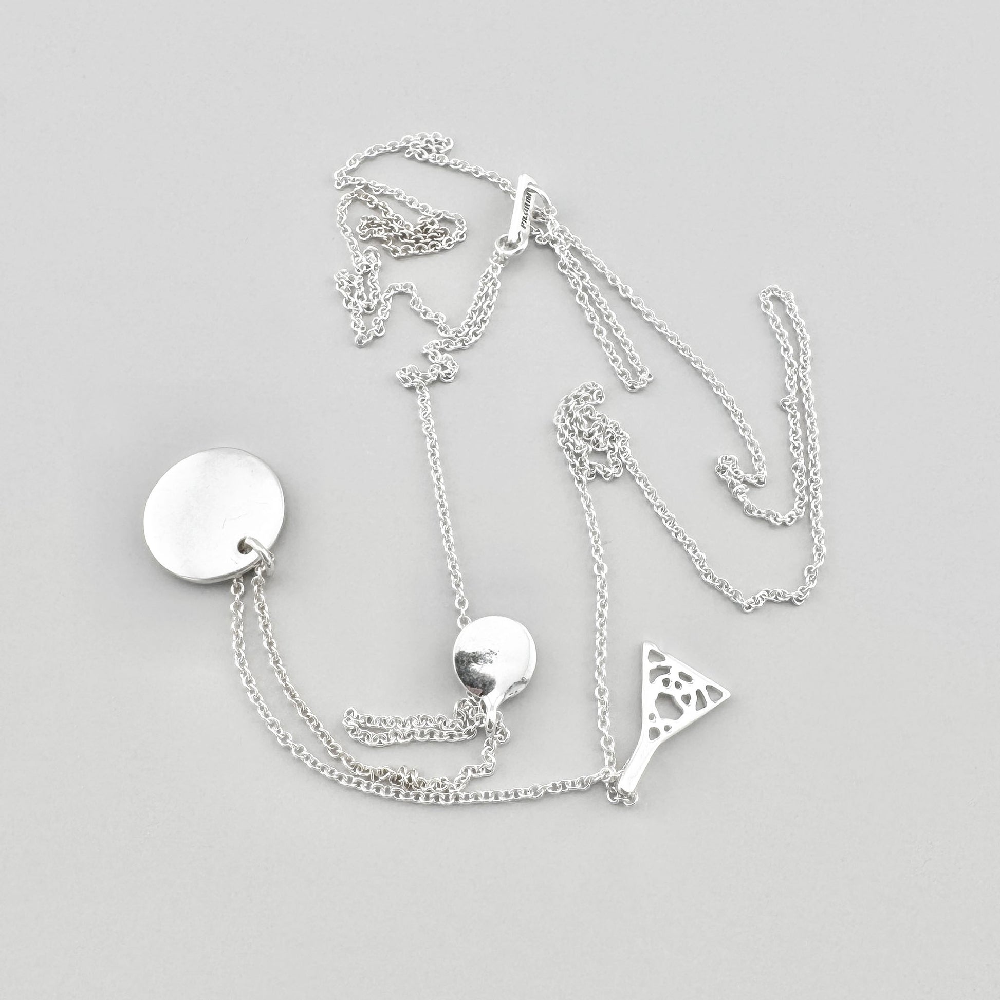 Pilgrim necklace with three pendants arranged on a light background with branded tag