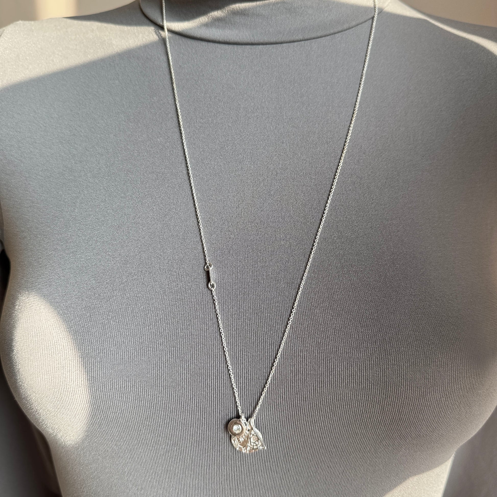 Long silver-tone Pilgrim necklace with tree of life, crystal and geometric charm worn on neck